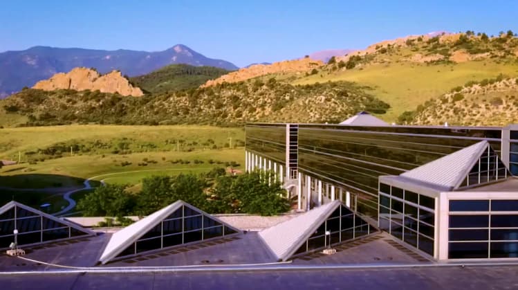 A modern building with angular roofs set against a mountainous backdrop