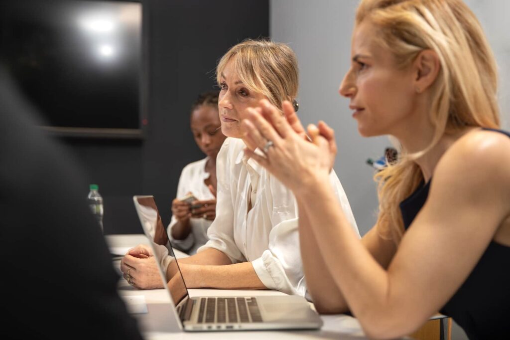 Several women listening to something while sitting in the office